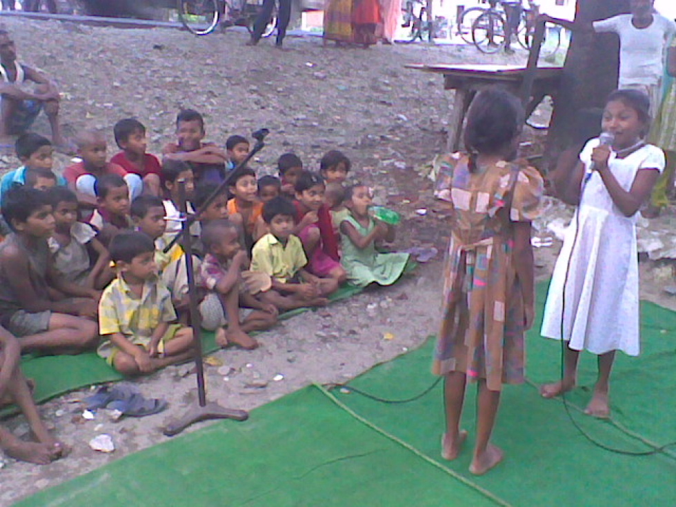 Children performing a role play in front of the community