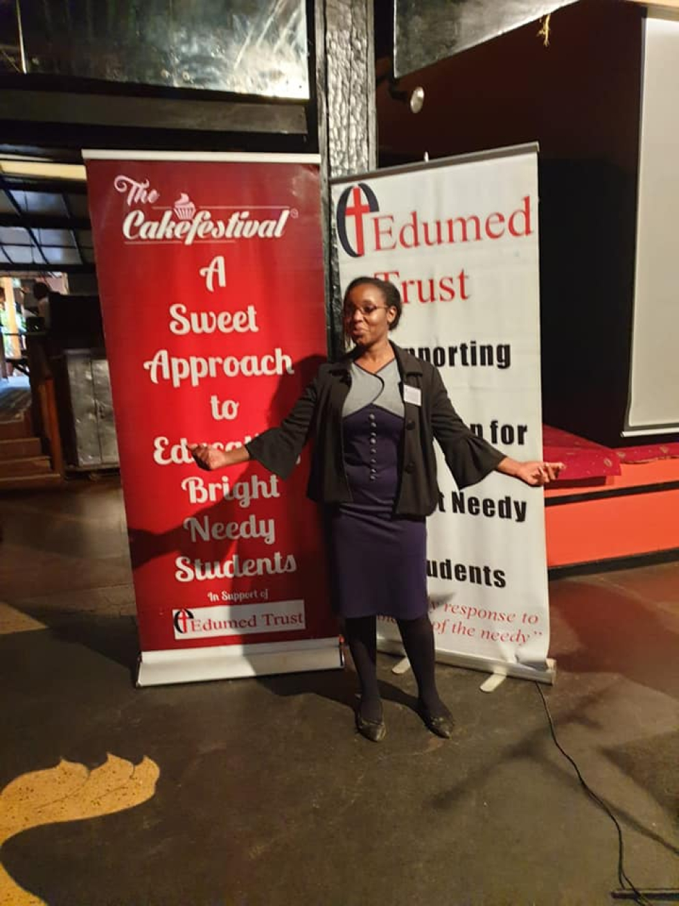 Coordinator Elizabeth Waichinga in front of the Cake Festival banners