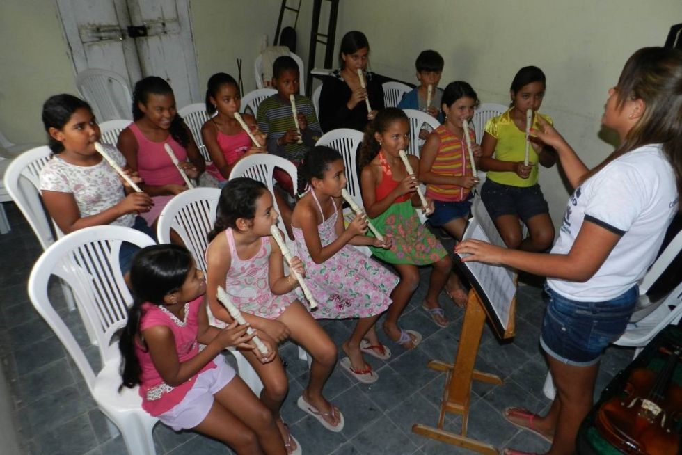 Meninas e meninos em sua primeira aula sendo orientados por uma jovem formada no mesmo projeto.